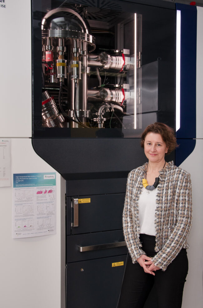 Dr. Jasna Jankovic vor dem Hochtemperatur-Umgebungsdruck-Röntgenphotoelektronen-Spektrometer (HT-NAP-XPS) am Fraunhofer ISE. (© Fraunhofer ISE)